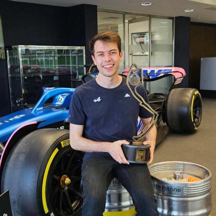 George Palozzi holding Monaco trophy in front of Alpine F1 Car